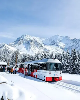 a red and white train stopped at a station in the snow at Studio Le Flocon à Saint-Gervais-les-Bains in Saint-Gervais-les-Bains
