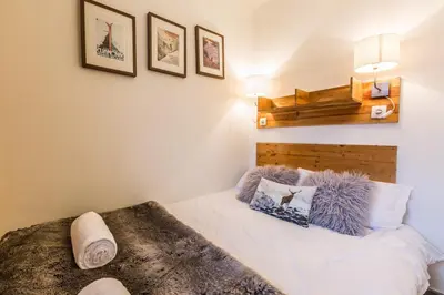 a bedroom with a white bed with a wooden headboard at Batiment F - A Chamonix Mont Blanc Panorama in Chamonix-Mont-Blanc