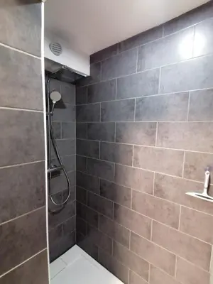 a bathroom with a shower and a tile wall at Au petit Névé in Les Houches