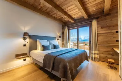 a bedroom with a bed and a large window at Le Chalet Baan - avec vue sur les montagnes in Combloux