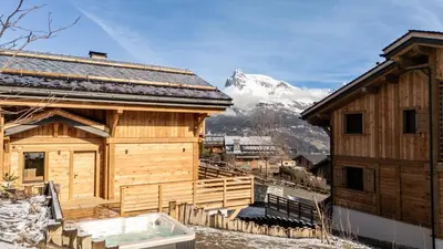 a wooden building with a hot tub in front of a mountain at Le Chalet Baan - avec vue sur les montagnes in Combloux