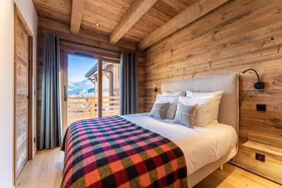 a bedroom with a bed with a wooden wall at Le Chalet Baan - avec vue sur les montagnes in Combloux