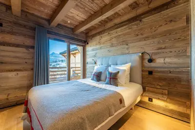 a bedroom with wooden walls and a bed with a window at Le Chalet Baan - avec vue sur les montagnes in Combloux