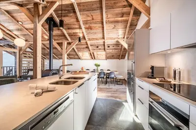 a kitchen with white cabinets and wooden ceilings at Chalet 4 Mésanges, Saint-Gervais -Le Bettex - by EMERALD STAY in Saint-Gervais-les-Bains