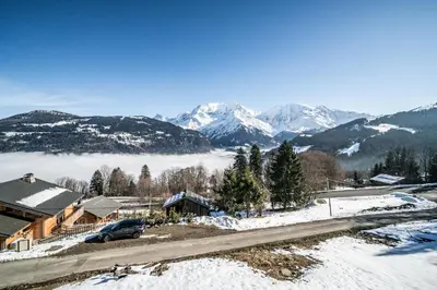 a house in the snow with mountains in the background at Chalet 4 Mésanges, Saint-Gervais -Le Bettex - by EMERALD STAY in Saint-Gervais-les-Bains