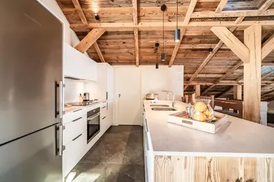 a kitchen with white cabinets and wooden ceilings at Chalet 4 Mésanges, Saint-Gervais -Le Bettex - by EMERALD STAY in Saint-Gervais-les-Bains