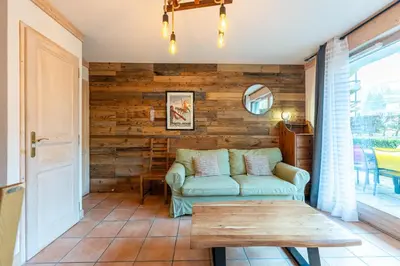 a living room with a green couch and a wooden wall at Le Regency - à 5 min à pied des pistes in Saint-Gervais-les-Bains