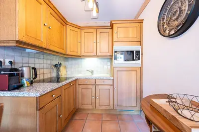 a kitchen with wooden cabinets and a microwave at Le Regency - à 5 min à pied des pistes in Saint-Gervais-les-Bains