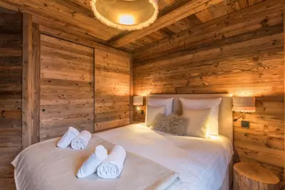 a bedroom with wooden walls and a bed with white pillows at Appartement Mady - Welkeys in Megève