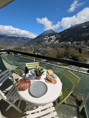 a table with a plate of food on a balcony at Appartement avec vue magnifique in Saint-Gervais-les-Bains