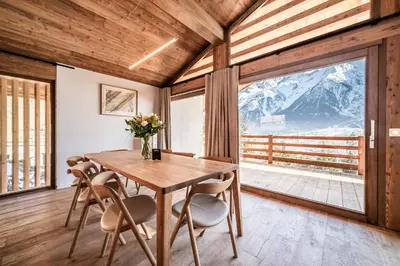 a dining room with a table and chairs and a large window at Chalet Foxden, Les Houches Chamonix - by EMERALD STAY in Les Houches