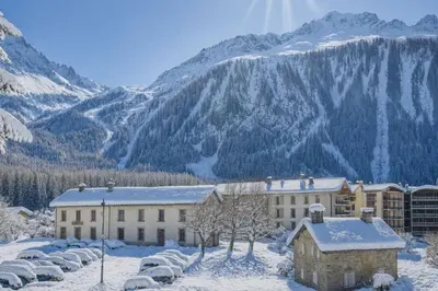 a building in the snow with mountains in the background at RUBY - Luxurious duplex 180 m2 in Chamonix-Mont-Blanc