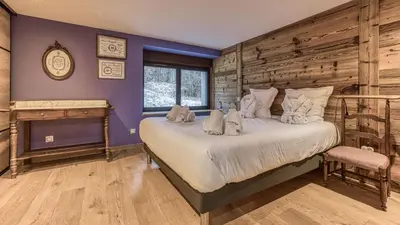 a bedroom with a large bed with a wooden wall at Chalet Grelettes in Les Houches