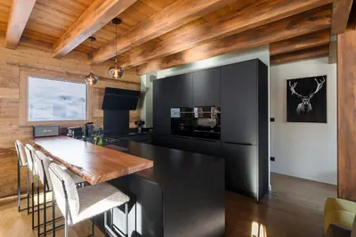a kitchen with a black island and a wooden ceiling at La Combe Blanche - Balcon sur le Mont-Blanc in Combloux
