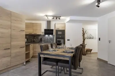 a dining room with a table and chairs in a kitchen at The Bear - Sauna Piscine - Face au Kandahar in Les Houches