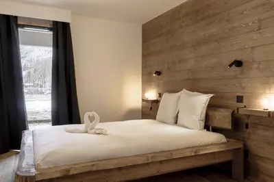 a bedroom with a large bed with a wooden wall at The Bear - Sauna Piscine - Face au Kandahar in Les Houches