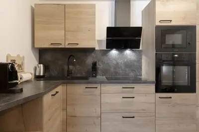 a kitchen with wooden cabinets and black appliances at The Bear - Sauna Piscine - Face au Kandahar in Les Houches