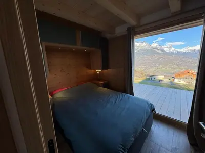 a bedroom with a bed and a large window at Le Mazot de L'Arpenaz in Combloux