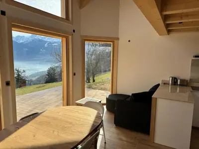 a living room with a table and a large window at Le Mazot de L'Arpenaz in Combloux