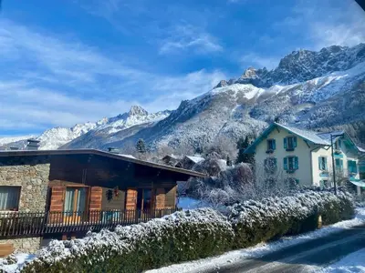a house with snow covered mountains in the background at Apartment Chamonix Brise du Mont in Chamonix-Mont-Blanc