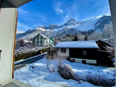 a house in the snow with mountains in the background at Apartment Chamonix Brise du Mont in Chamonix-Mont-Blanc