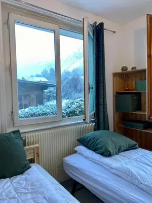 two beds in a room with a window at Apartment Chamonix Brise du Mont in Chamonix-Mont-Blanc