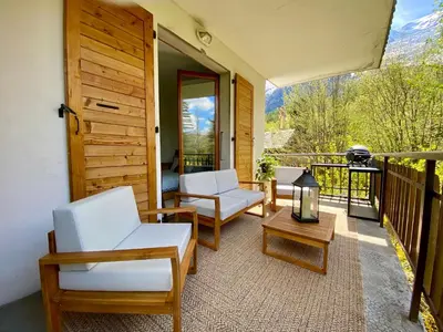 a porch with two chairs and a table on a balcony at Apartment Chamonix Brise du Mont in Chamonix-Mont-Blanc