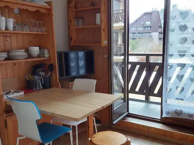 a wooden table and chairs in a room with a window at Appartement cosy avec balcon et parking à Chamonix, proche centre-ville - FR-1-517-70 in Chamonix-Mont-Blanc