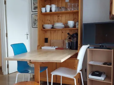 a dining room table with chairs and a television at Appartement cosy avec balcon et parking à Chamonix, proche centre-ville - FR-1-517-70 in Chamonix-Mont-Blanc