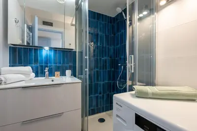 a bathroom with a sink and a shower with blue tiles at Appartement des Champs - Welkeys in Chamonix-Mont-Blanc