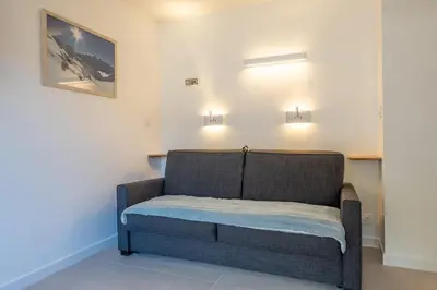 a couch in a room with two lights on the wall at Appartement des Champs - Welkeys in Chamonix-Mont-Blanc