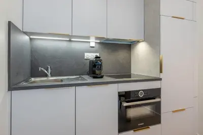 a kitchen with white cabinets and a sink at Appartement des Champs - Welkeys in Chamonix-Mont-Blanc
