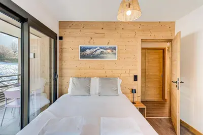 a bed in a room with a wooden wall at Apartment Annapurna, Alpes Travel, Les Houches, Sleeps 5 in Les Houches