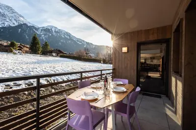 a table with purple chairs on a balcony with mountains at Apartment Annapurna, Alpes Travel, Les Houches, Sleeps 5 in Les Houches