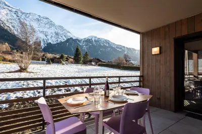 a table with purple chairs and a view of a snowy mountain at Apartment Annapurna, Alpes Travel, Les Houches, Sleeps 5 in Les Houches