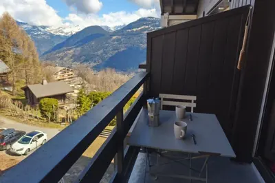 a blue table on a balcony with a view of mountains at Cozy Apartment with Balcony Saint-Gervais in Saint-Gervais-les-Bains