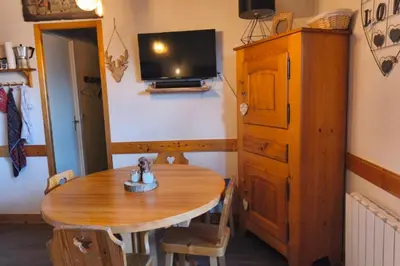a room with a wooden table and a tv on a wall at Cozy Apartment with Balcony Saint-Gervais in Saint-Gervais-les-Bains