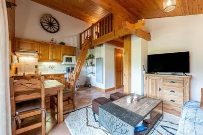 a living room with a table and a kitchen at Appartement aux Houches Pied des pistes in Les Houches