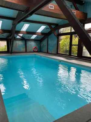 an indoor swimming pool with blue water at Appartement aux Houches Pied des pistes in Les Houches