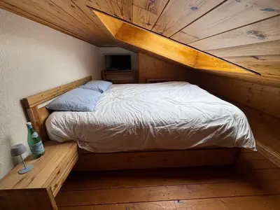 a bed in a room with a wooden ceiling at Appartement aux Houches Pied des pistes in Les Houches