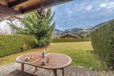 a wooden table sitting on a deck in a yard at Appartement Piton - Welkeys in Megève