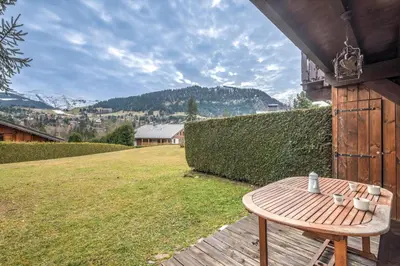 a wooden table sitting on a porch with a yard at Appartement Piton - Welkeys in Megève