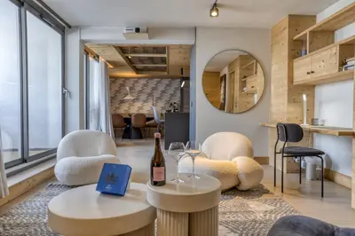 a living room with two chairs and a bottle of wine at Megeve les skis aux pieds in Megève