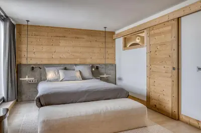 a bedroom with a bed and a wooden wall at Megeve les skis aux pieds in Megève