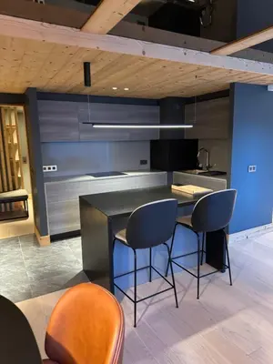 a kitchen with a black counter and some chairs at Megeve les skis aux pieds in Megève