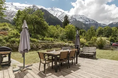 a wooden deck with a table with chairs and umbrellas at Pierre Belle - 80m2 - Grande Terrasse et Jardin in Chamonix-Mont-Blanc