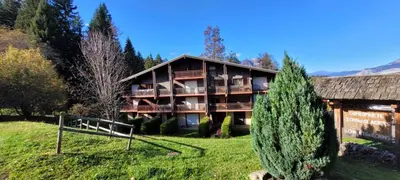 a large building on a grassy hill with trees at Studio Cosy 4 personnes avec jardin in Combloux