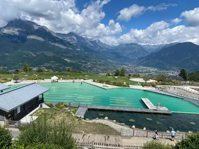 a large pool of water with mountains in the background at Studio Cosy 4 personnes avec jardin in Combloux