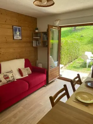 a living room with a red couch and a sliding glass door at Studio Cosy 4 personnes avec jardin in Combloux