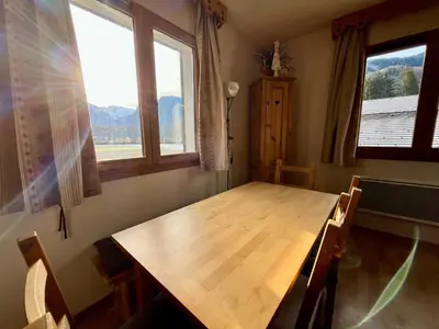 a wooden table in a room with two windows at Appartement T2 6 pers avec Wifi et parking couvert - FR-1-629-145 in Samoëns